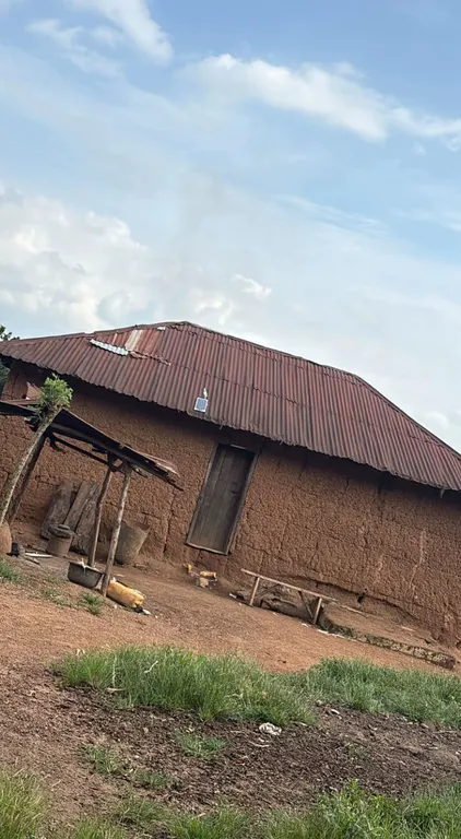 The untreated house photograph, with distinct clouds above a corrugated roof and grass in the foreground.