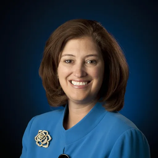 Untreated square head-and-shoulders portrait, with the face centered against a dark blue background.